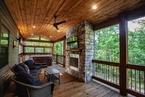 Broken Bow Cabins Texas Time furniture and fireplace on covered patio deck